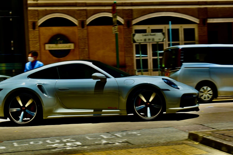 a silver sports car is parked in front of an old brick building on the street