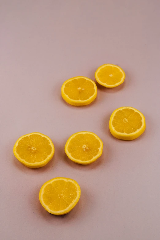 eight oranges cut in half on top of a pink table