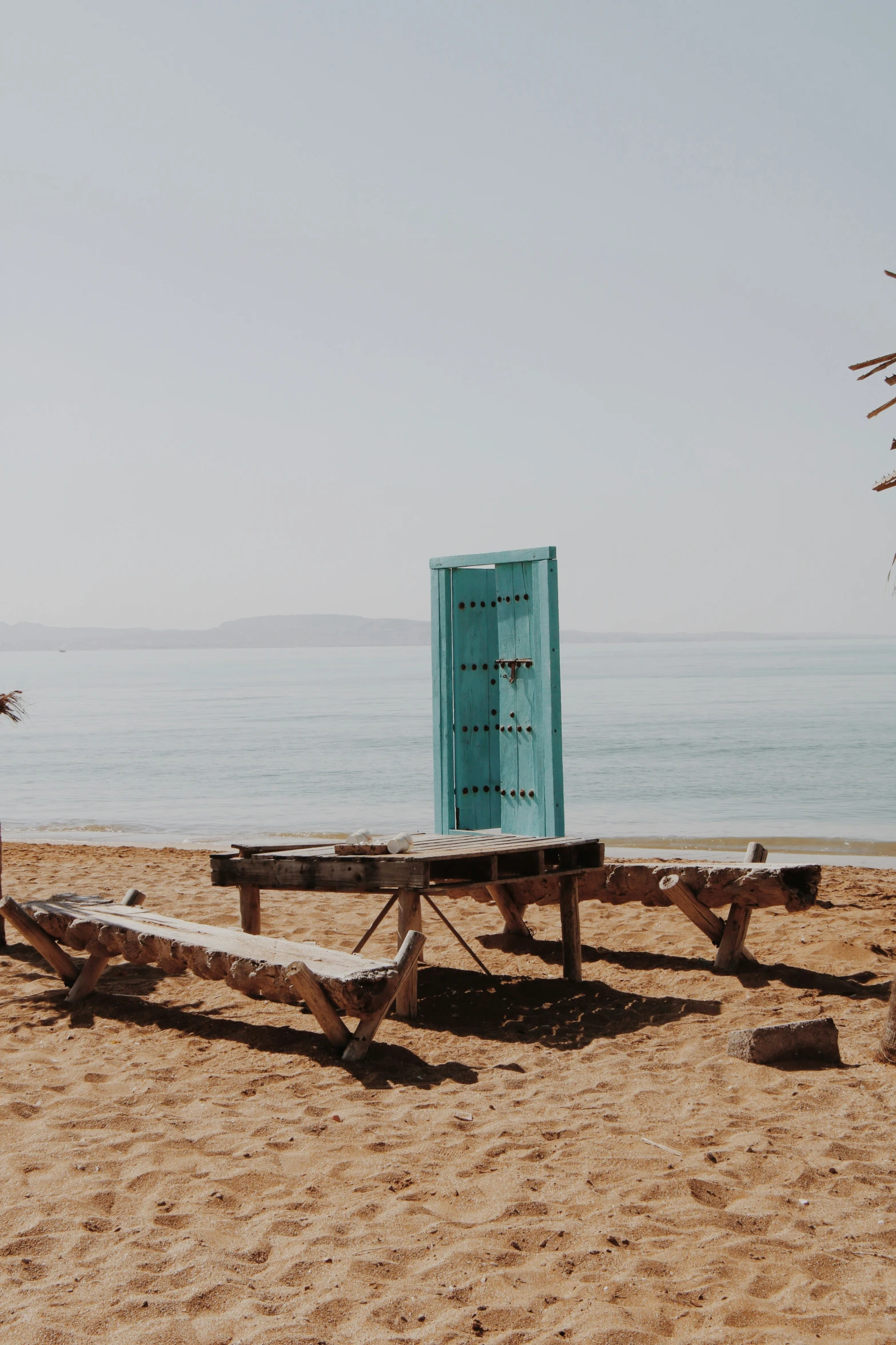 an outhouse on the beach with a blue door