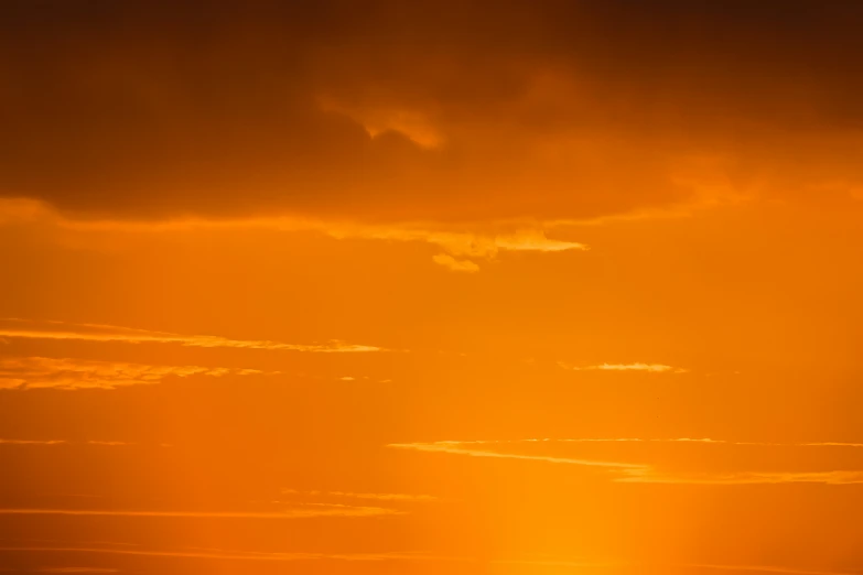 a plane flying across a yellow and red sky