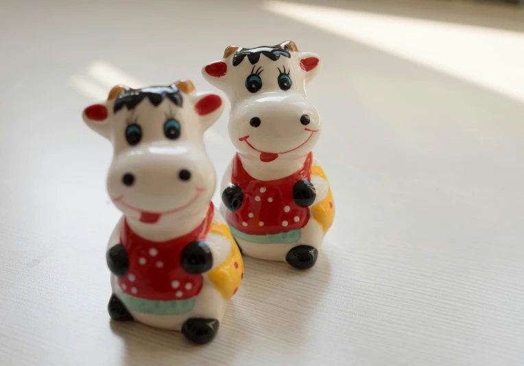 two ceramic toy cows are on the table