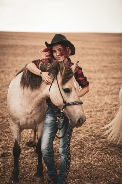 a man wearing a hat, plaid shirt and jeans is sitting on a pony