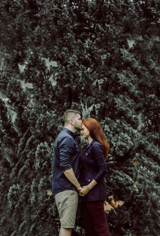 couple standing in front of trees together in a park