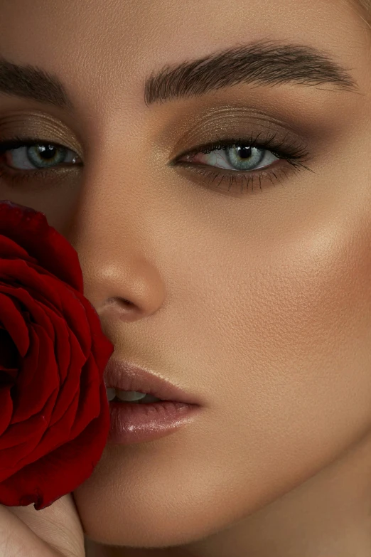 a woman holding a red rose up to her face