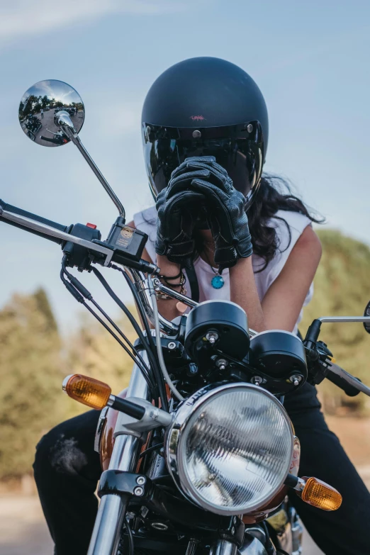 woman on motorcycle wearing a helmet and sunglasses