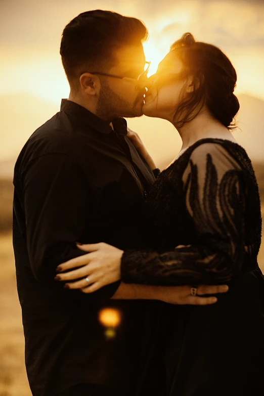 a man and woman kissing under the sunset