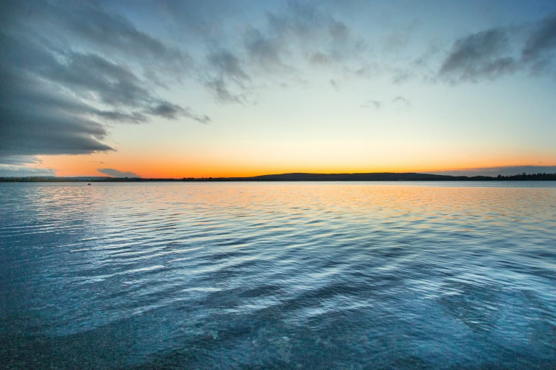 sunset over the ocean with ripples in the water