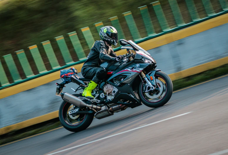 person wearing black and green clothing riding a red motorcycle