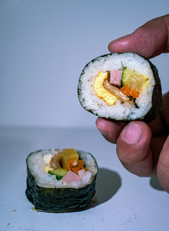 a person holding some sushi with rice and sauce
