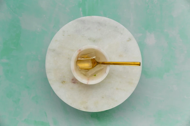 a marble bowl filled with liquid next to a yellow spoon