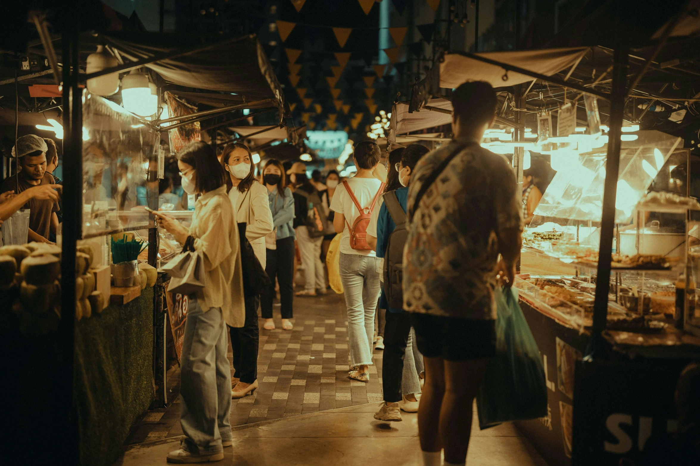 a busy street market with lots of people looking at food