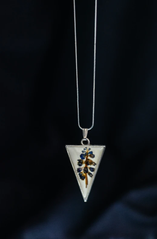 a triangle shaped pendant hanging from a chain