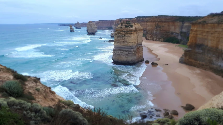 a sandy beach sits next to a large rocky cliff