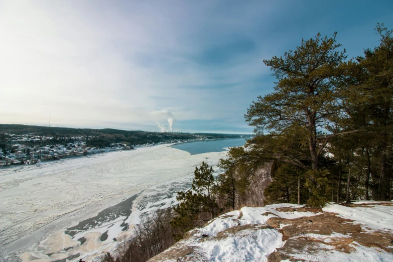 a snow covered hillside overlooks water and trees