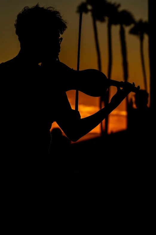 a man playing a guitar silhouetted against the sunset