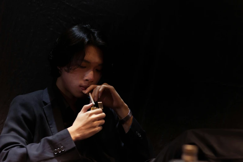 an asian man smoking a cigarette while sitting in front of a table