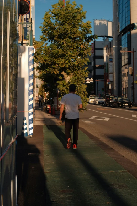 a man wearing a white shirt is riding a skateboard down the street