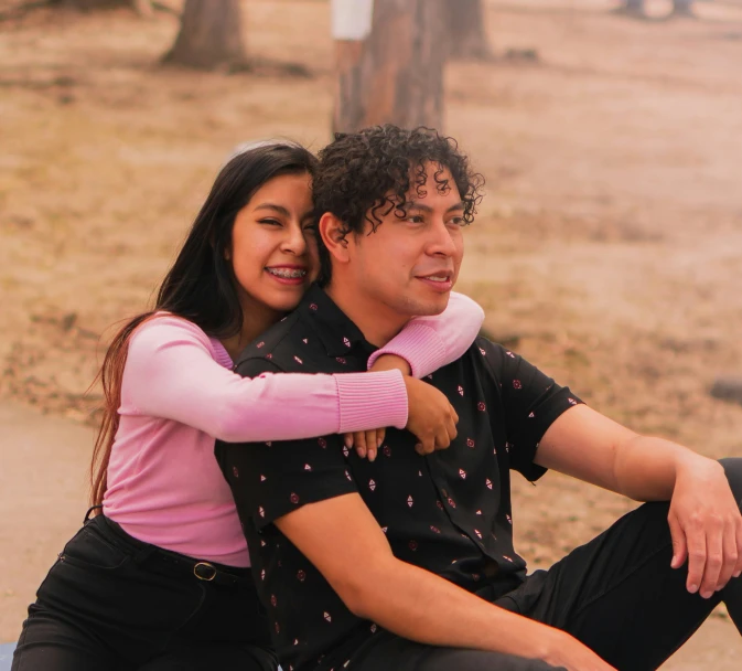 a young man and woman sitting together on a stone bench