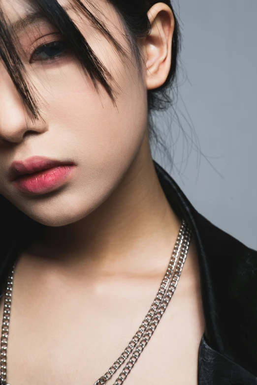 a woman is wearing silver chain necklace with white background