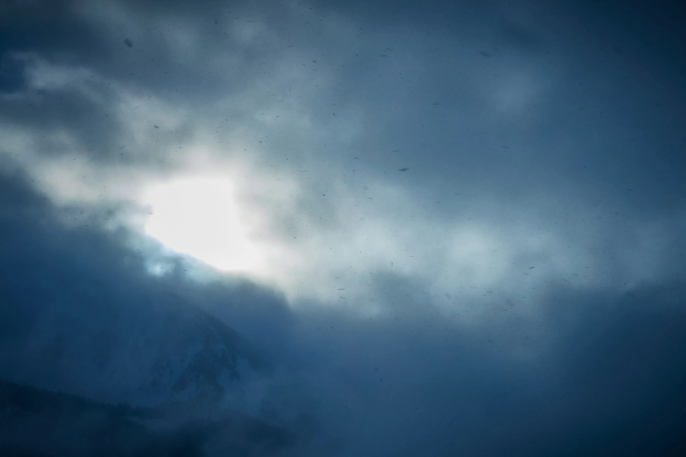 clouds loom over the top of a snowy mountain