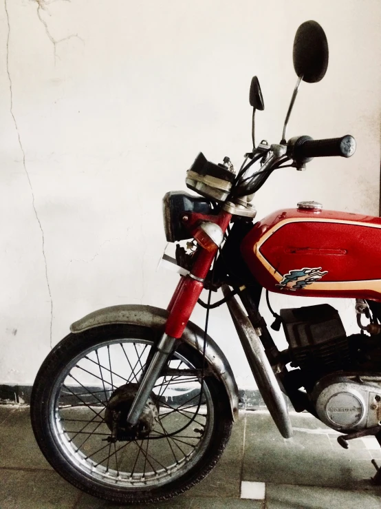 a red and black motorcycle parked next to a wall