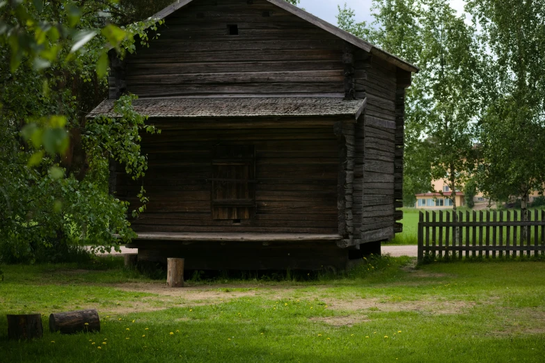 a wood cabin and a fence in a grassy area