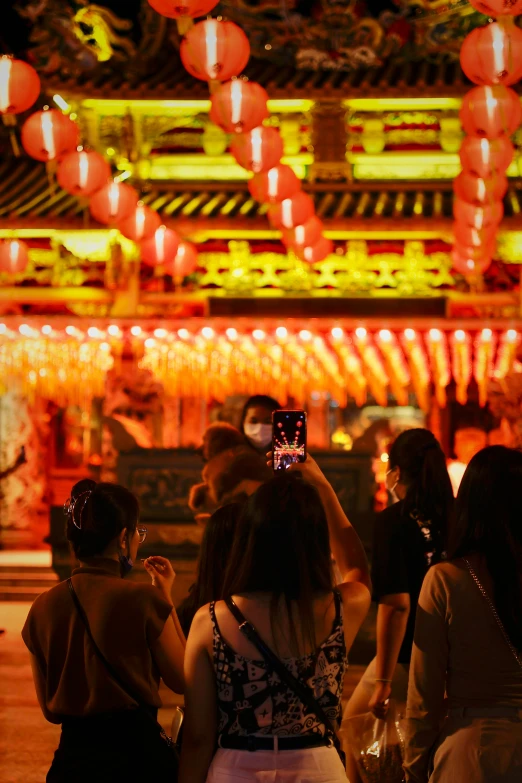 two women taking pictures of a building with lanterns