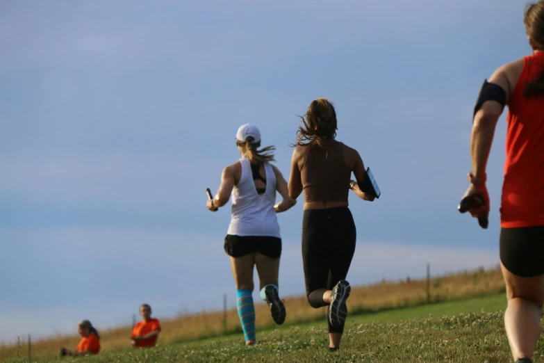 two runners running near a field with sky in background