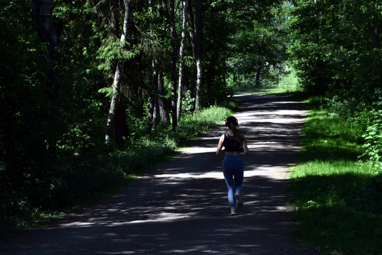 a woman is walking down the road in the woods