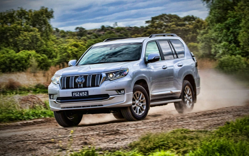 a silver nissan suv drives along a muddy road