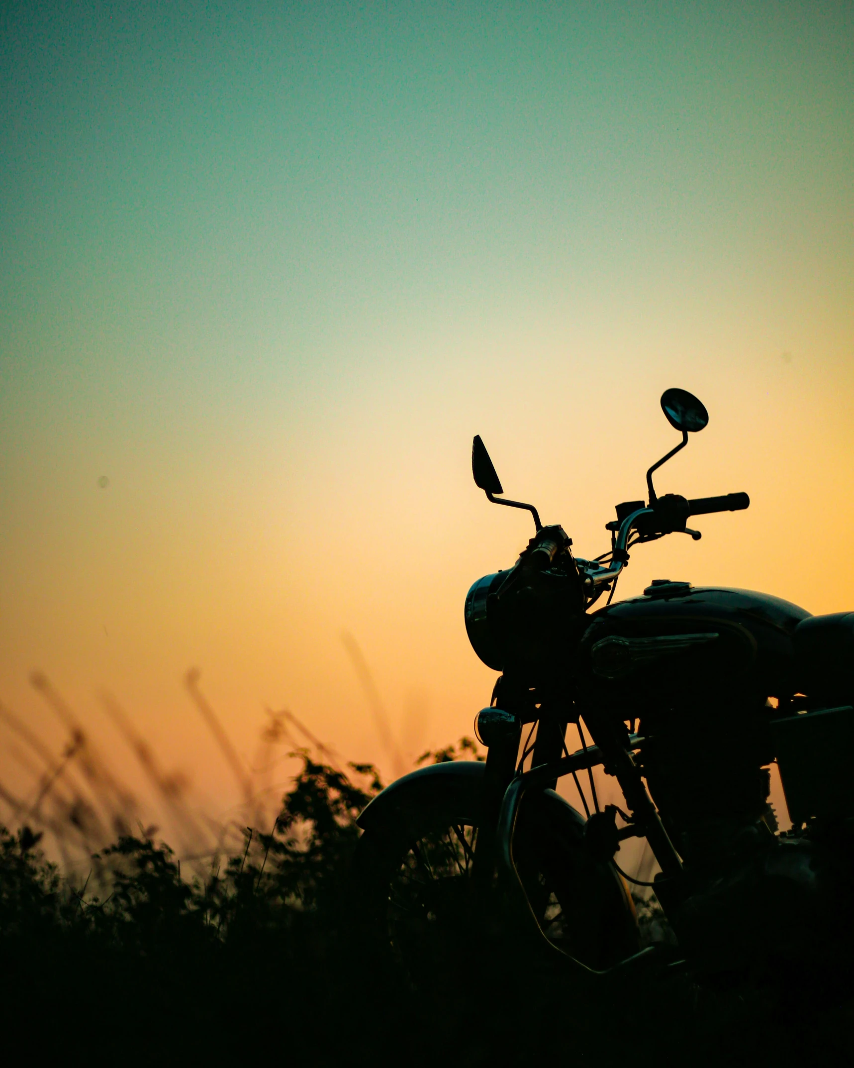 an old motorcycle is parked with the sun in the background