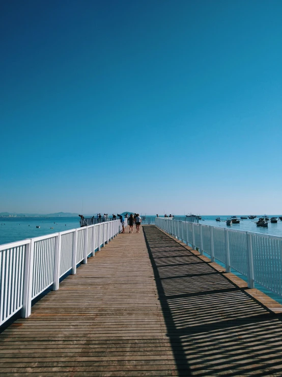 a pier with people walking on it along the water