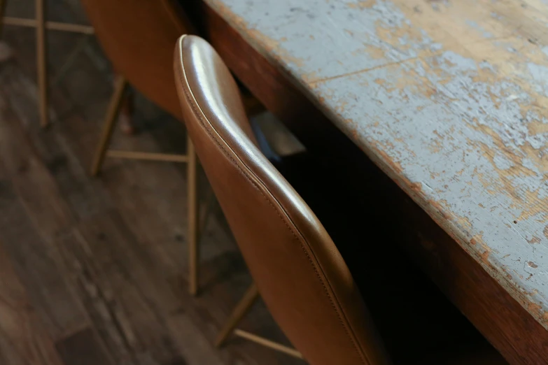 an old, brown chair sits at a gray table