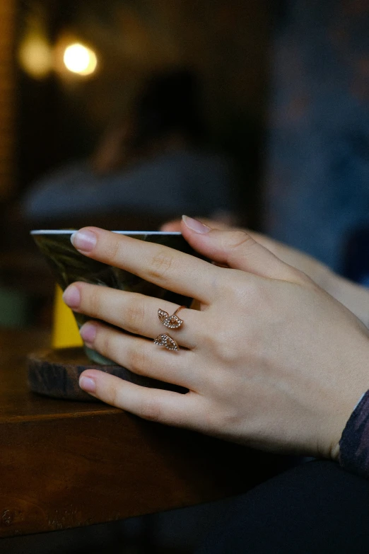 two hands with rings holding a smart phone