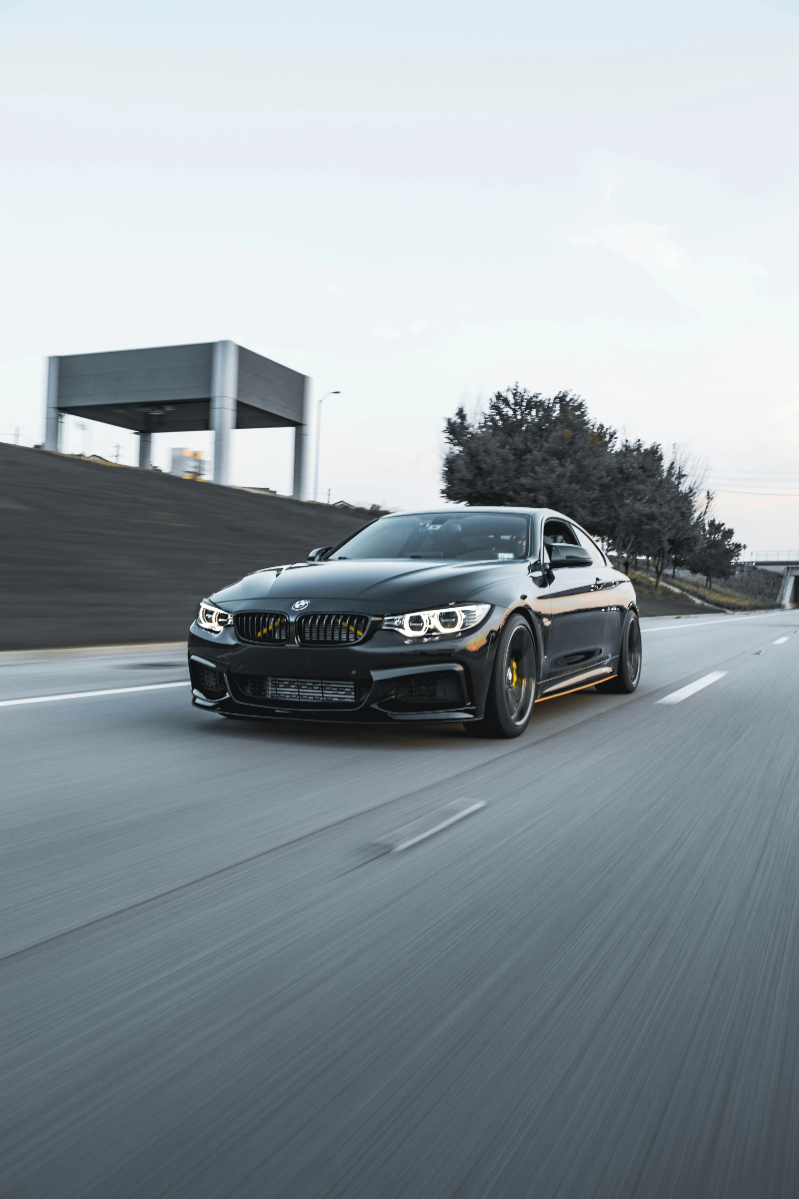 a black and gold bmw car driving on an empty road