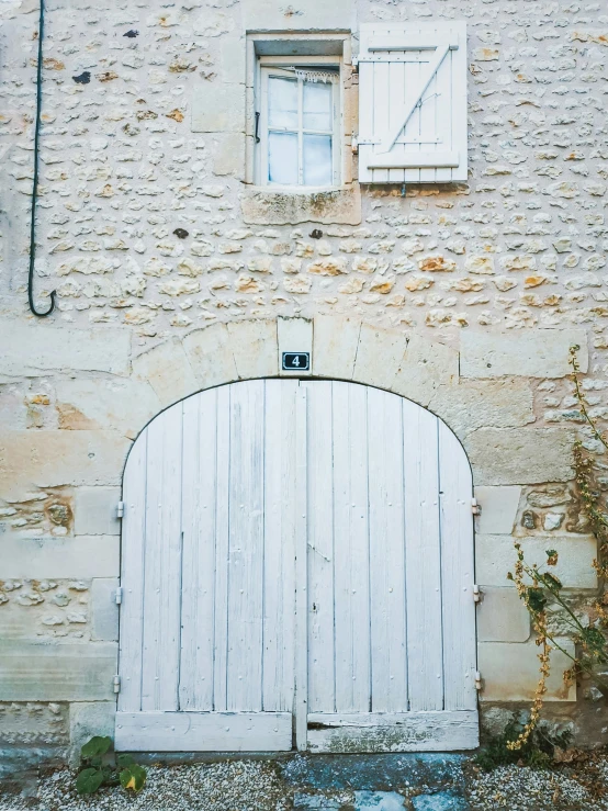 an arched white door is behind a stone building