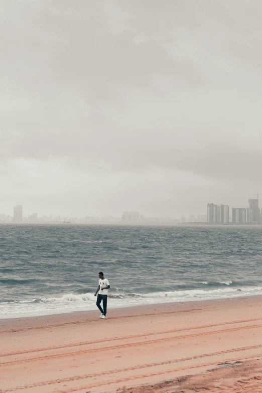 person on a beach flying a kite on a cloudy day