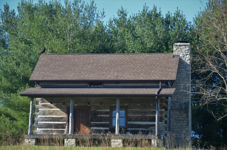 the log cabin sits outside beside some trees