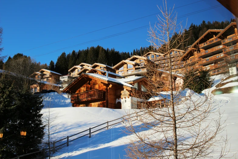 snow covered hillside with wooden cabins in the distance