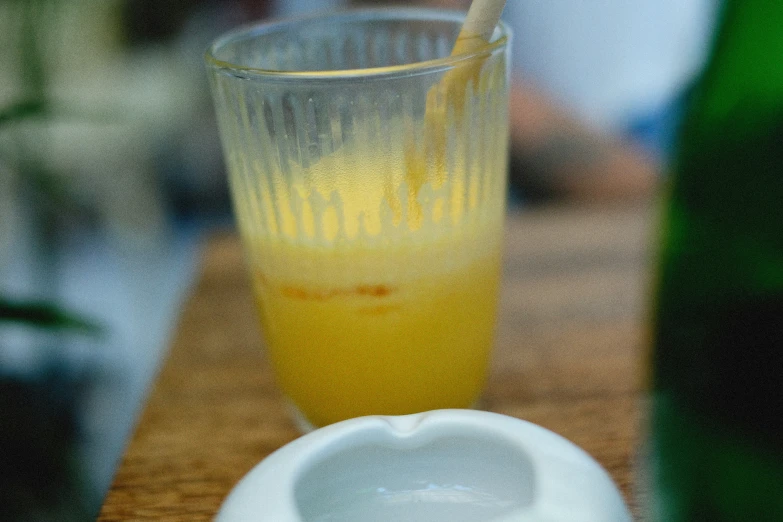 the glass is full of liquid that is near a bowl and bottle