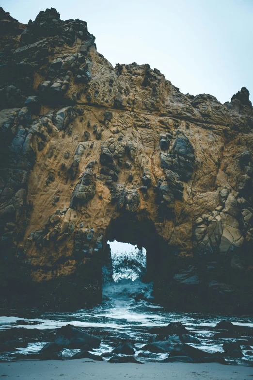 a rocky beach with a natural cave in the middle