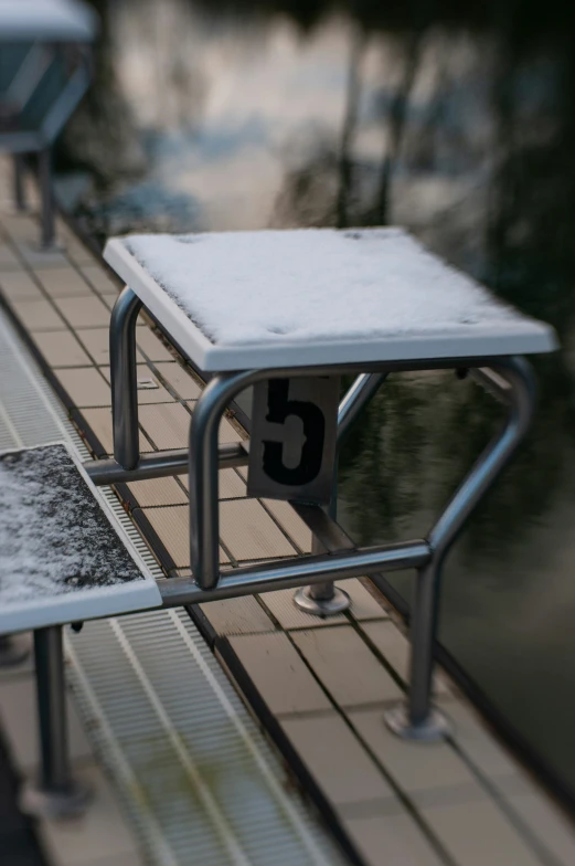 the bench is covered in snow next to the water