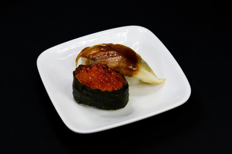 a square plate filled with sushi and sauce