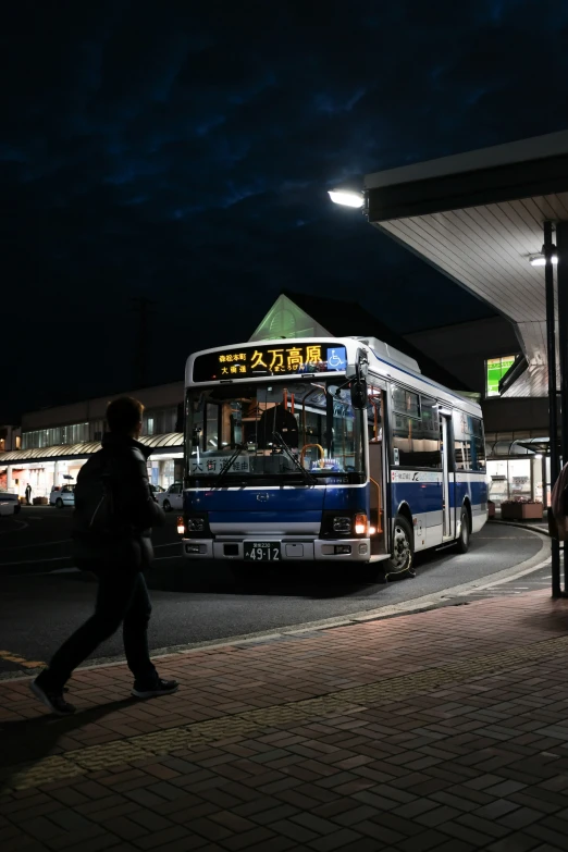 a person walking by a blue and white bus