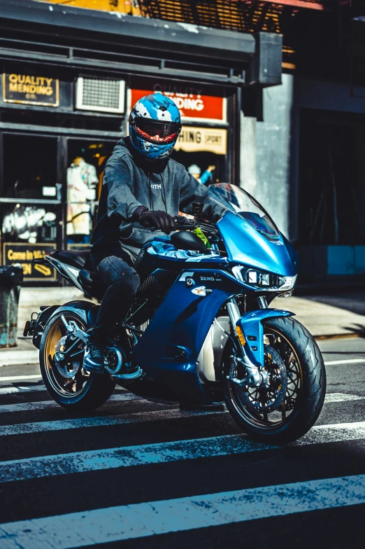 the man is riding a blue motorcycle on the road