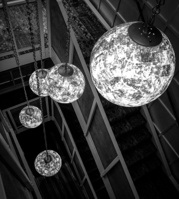 some lamps hanging from the ceiling next to a set of stairs