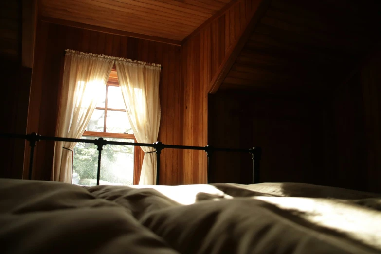 an open window in a dark bedroom, with sheets and blankets folded