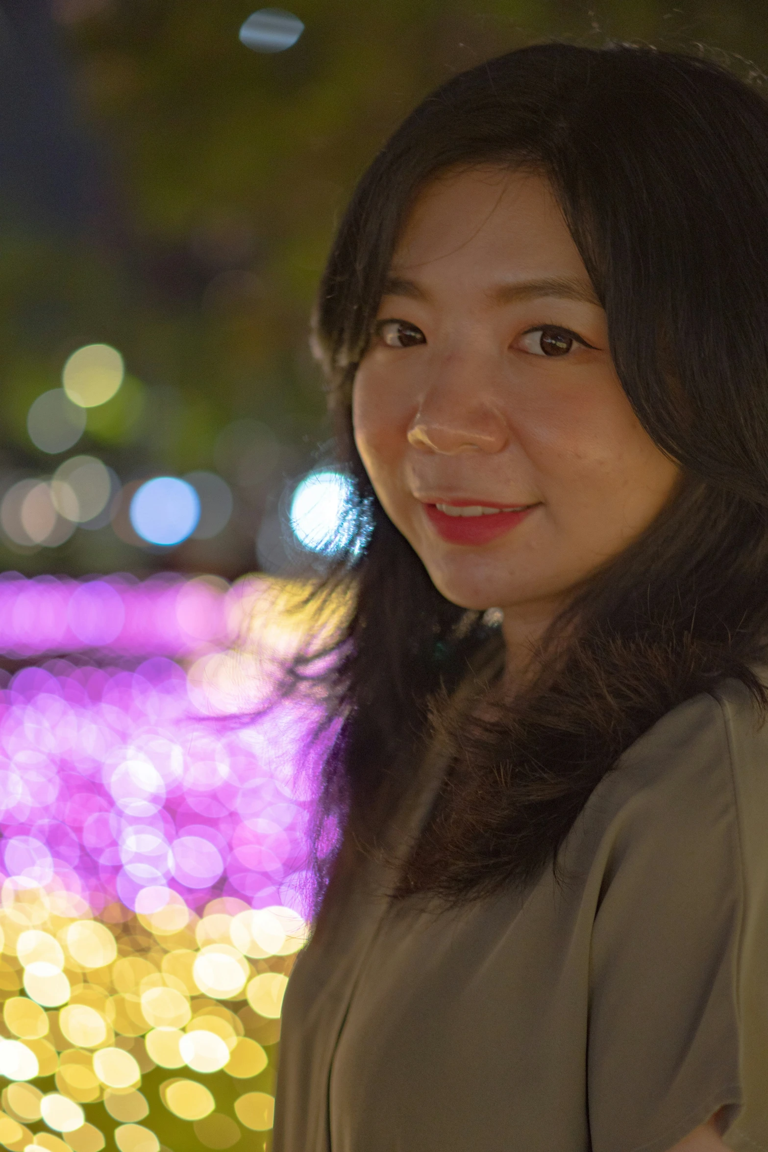 a woman poses in front of brightly lit lights