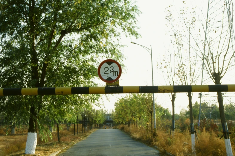 a red and white speed limit sign above a street