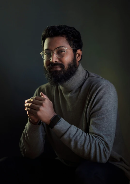 man sitting with his hands folded, lighting up by candle